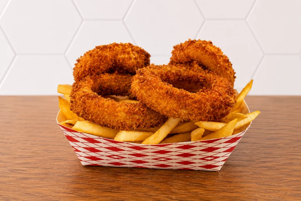 Half and Half: Basket of crispy onion rings and golden French fries served together.