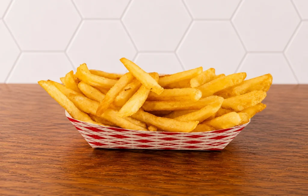 Reg Fries Pic: Classic basket of golden French fries served in a red checkered tray.