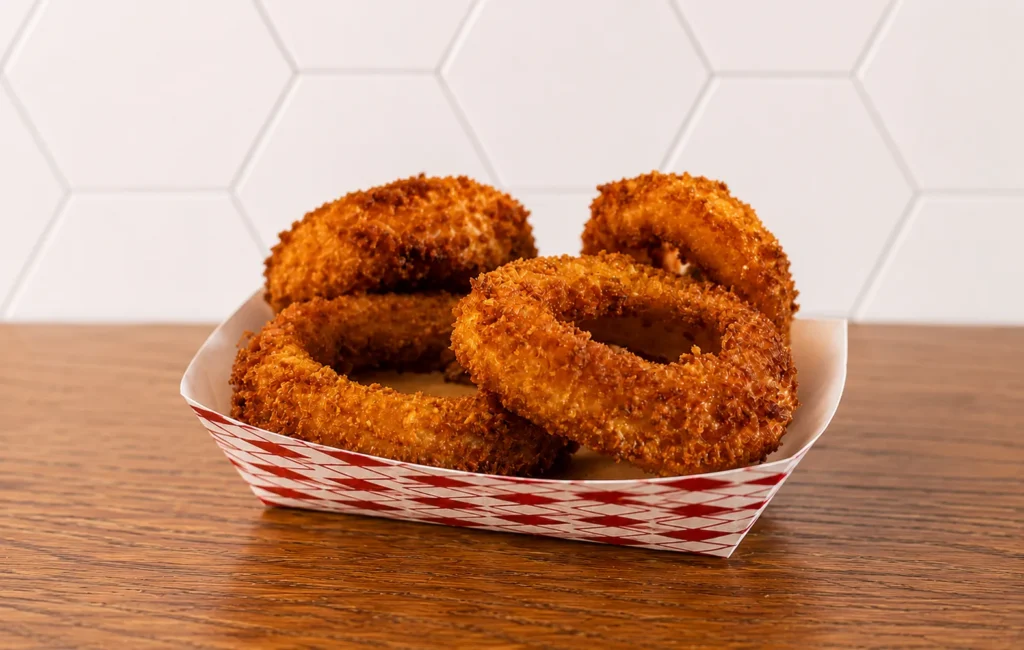 Onion Ringss: Crispy golden onion rings served in a basket with a crunchy coating.