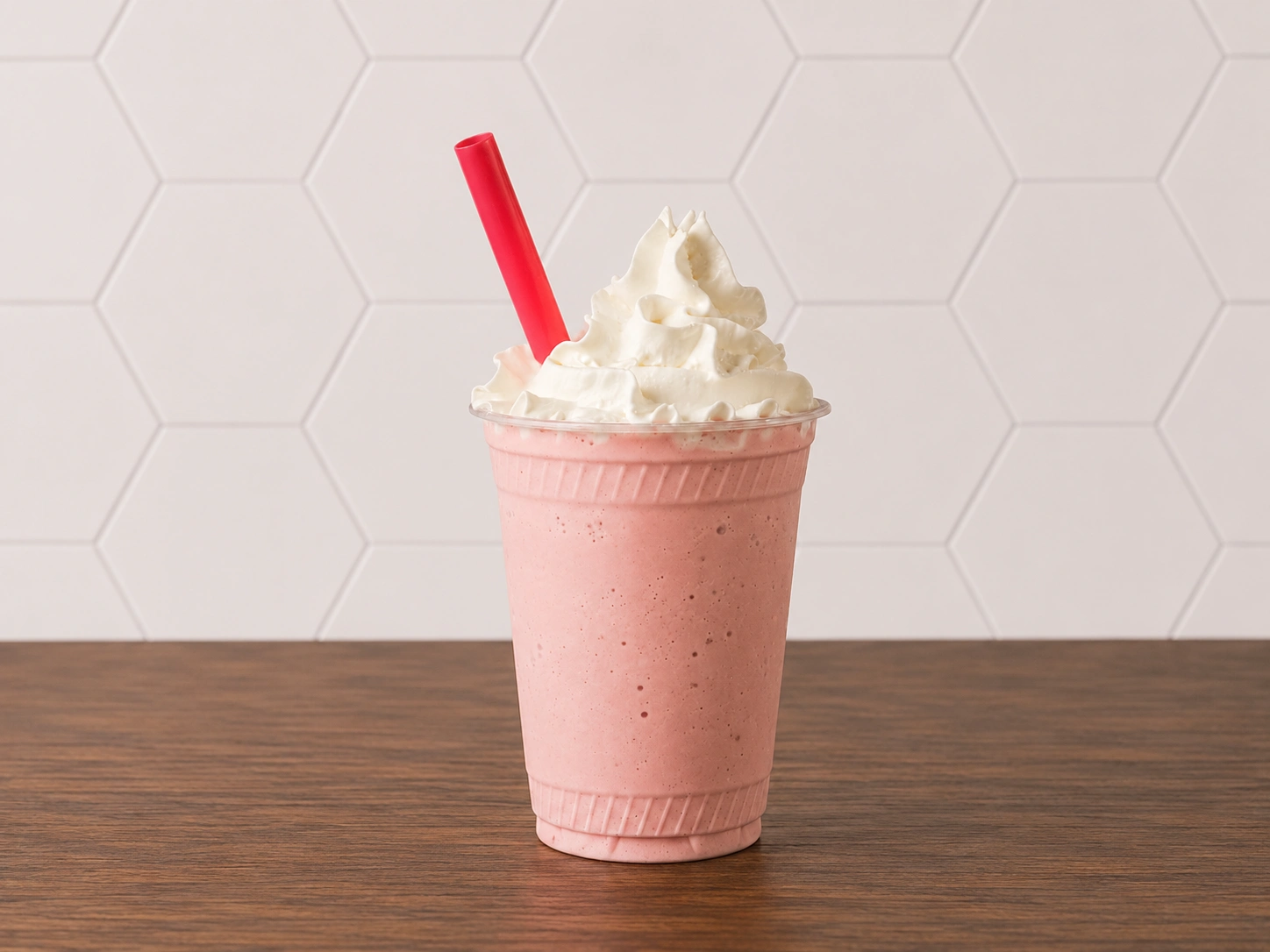 Strawberry Milkshake: Strawberry milkshake topped with whipped cream and served in a classic shake cup.
