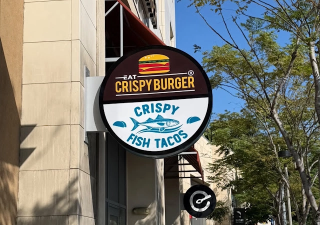 Sign on a building advertising crispy fish tacos, featuring vibrant colors and appealing graphics.